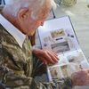 Hale looks through an album of photos from the Normandy invasion. The swirling substance on the pages is sand from a Normandy beach that his daughter-in-law arranged on the pages.