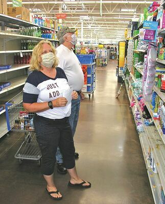 Two customers at the Norton Walmart comply with the mask requirement while shopping shortly after noon Friday. By a reporter’s observations, roughly half the customers inside were not wearing any face covering.  JEFF LESTER PHOTO